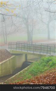 Autumn foggy morning - foot bridge in autumnal misty park.
