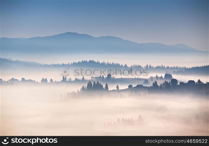 Autumn foggy morning in Carpathian mountains. Alpine village on the hills