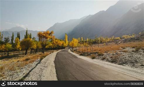 Autumn foliage in Thorgo with a view of mountain range. Colorful trees along the empty road in Skardu. Gilgit Baltistan, Pakistan.