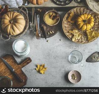 Autumn food background with pumpkins, cutting board and knife, various spices and kitchen utensils. Top view