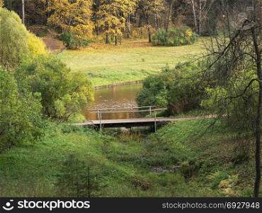 Autumn forest and wooden bridge across the river