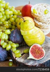 Autumn, fresh fruits. In the foreground are sliced figs and a pear located on a wooden tray. Close-up.