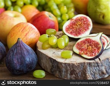 Autumn, fresh fruits. In the foreground, sliced figs located on a wooden tray. Close-up.