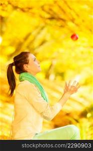 Autumn fruits, nature concept. Woman relaxing in park or autumnal forest throwing apple.. Woman relaxing in park holding apple fruit