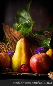 Autumn fruits on dark rustic kitchen table at wooden background, side view, close up, still life