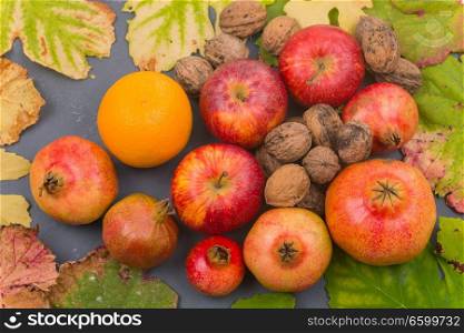 Autumn fruits still life among leaves on wooden table