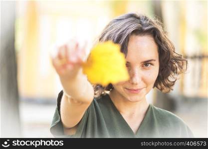 autumn - fun girl holds a yellow leaf