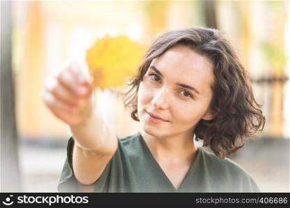 autumn - fun girl holds a yellow leaf
