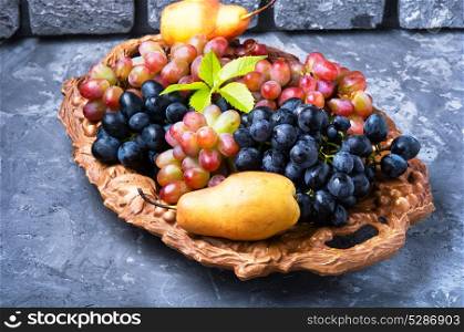 autumn grape and pear. Harvest of autumn grapes and ripe pear on a tray