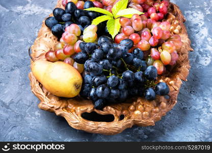 autumn grape and pear. Harvest of autumn grapes and ripe pear on a tray