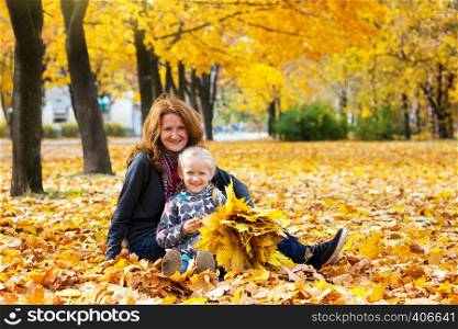 autumn. happy family - smiling mother with daughter outdoors throw yellow maple leaves
