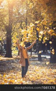 autumn. happy smiling girl outdoors throw yellow maple leaves