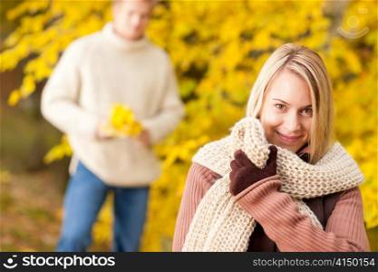 Autumn happy young woman in park with man in background