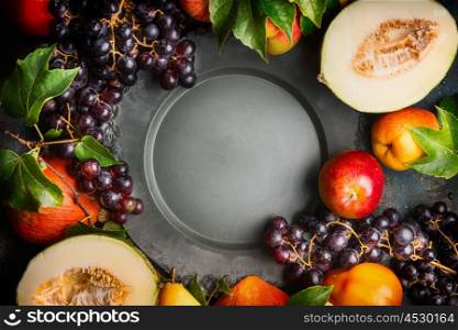 Autumn harvest fruits and vegetables around blank dark vintage dish, top view frame, horizontal