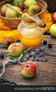 Autumn harvest of apples in the background of the glass jar with fragrant honey