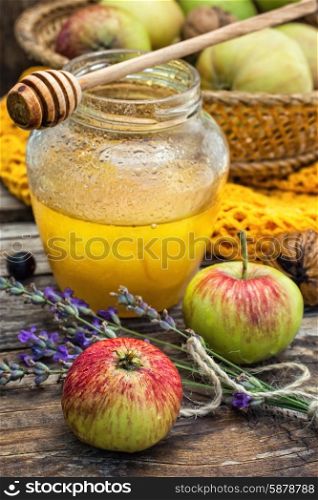 Autumn harvest of apples in the background of the glass jar with fragrant honey.