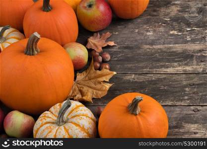 Autumn harvest on wooden table. Autumn harvest still life with pumpkins, apples, hazelnut and maple leaves on wooden background
