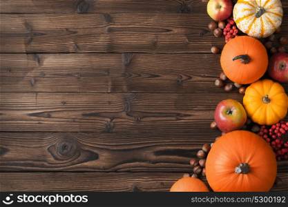 Autumn harvest on wooden table. Autumn harvest still life with pumpkins, apples, hazelnuts and rowanberry on wooden background, top view