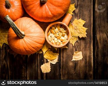 Autumn harvest. Pumpkin seeds with the maple leaves. On a wooden table.. Pumpkin seeds with the maple leaves.
