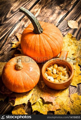 Autumn harvest. Pumpkin seeds with the maple leaves. On a wooden table.. Pumpkin seeds with the maple leaves.