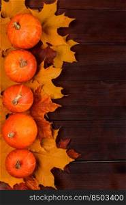 Autumn harvest. Ripe pumpkins and fallen leaves on a wooden background. Thanksgiving and halloween concept. Copy space.. Autumn harvest. Ripe pumpkins and fallen leaves on wooden background. Thanksgiving and halloween concept.