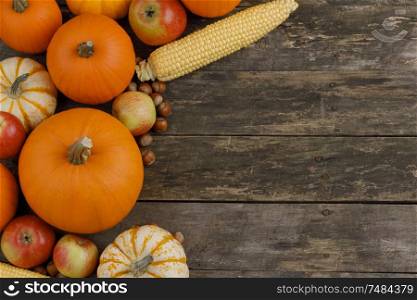 Autumn harvest still life with pumpkins, apples, hazelnut, corn, on wooden background, top view with copy space. Autumn harvest on wooden table