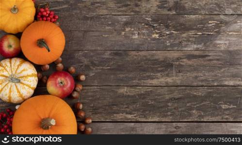 Autumn harvest still life with pumpkins , apples , hazelnuts on wooden background , top view. Autumn harvest on wooden table
