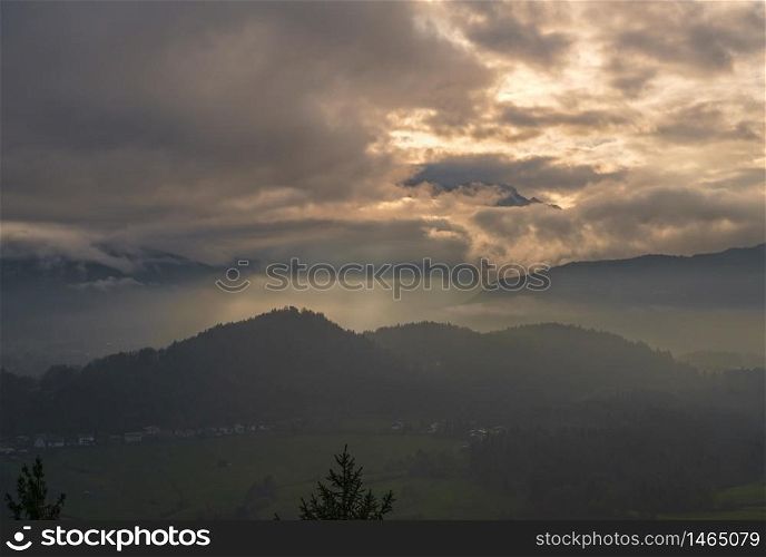 Autumn hazy day Berchtesgadener Land and mount Watzmann silhouette fragments in contra light cloudy view from Marxenhohe viewpoint, Bavarian prealps, Germany