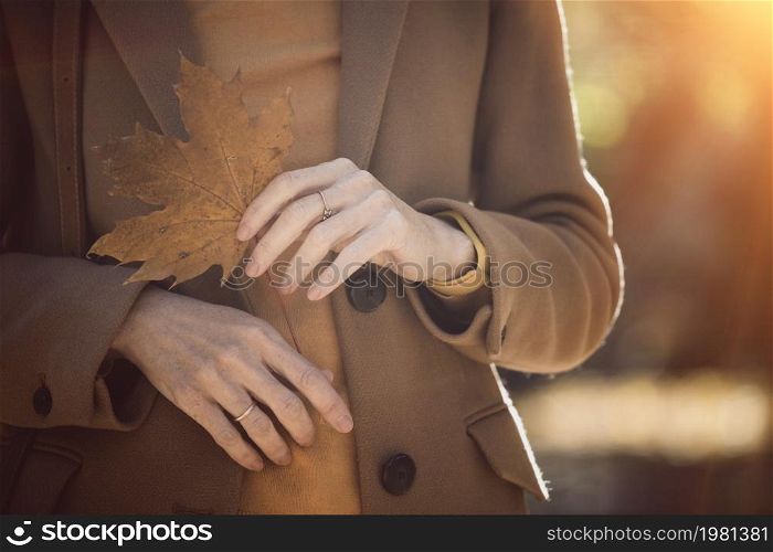 autumn in the city. girl holding a yellow leaf in her hand. accessories and parts