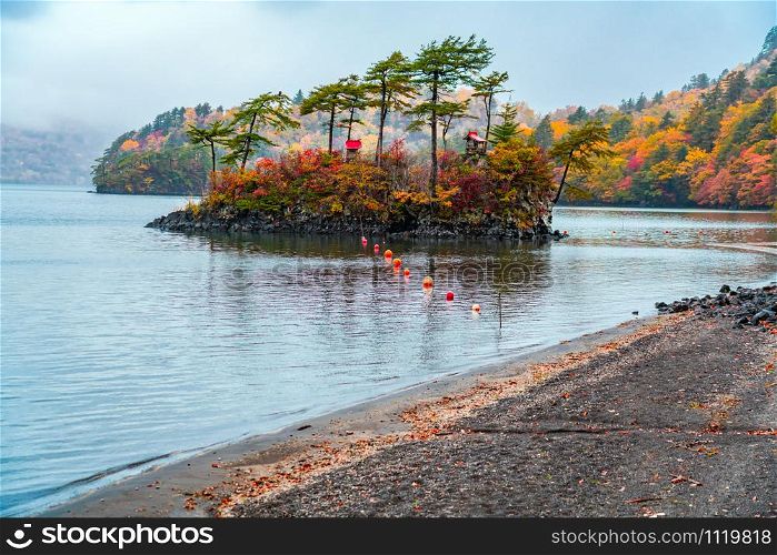 Autumn landscape of Lake Towada in raining day with the colorful foliage at the forest in the town of Yasumiya, Towada Hachimantai National Park, Aomori Prefecture, Japan.
