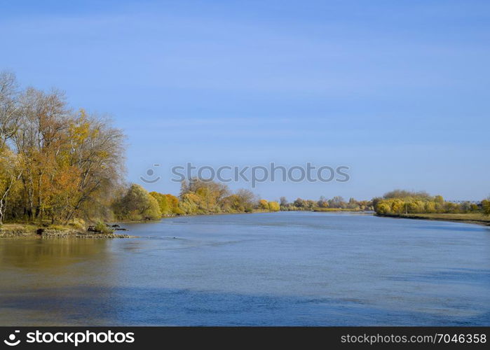 Autumn landscape. River bank with autumn trees. Poplars on the banks.. Autumn landscape. River bank with autumn trees. Poplars on the b