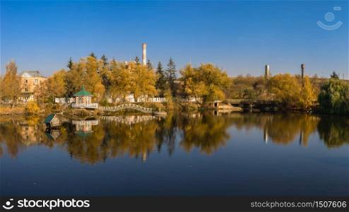 Autumn landscape with a lake and yellow trees in the village of Ivanki, Cherkasy region, Ukraine, on a sunny autumn evening. Autumn landscape with a lake and yellow trees