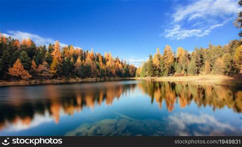 Autumn landscape with fantastic colors of plains reflected in Laj Nair in the valley Engadine Switzerland