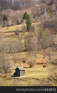 autumn landscape with the trees on a mountain hill and wooden hut