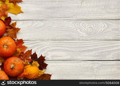 Autumn leaves and pumpkins over old wooden background . Autumn leaves and pumpkins over old wooden background with copy space