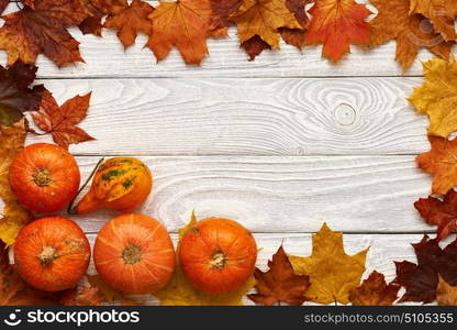 Autumn leaves and pumpkins over old wooden background with copy space