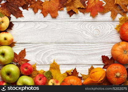 Autumn leaves, apples and pumpkins over old wooden background with copy space