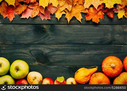Autumn leaves, apples and pumpkins over old wooden background with copy space