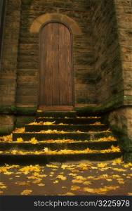 Autumn Leaves Lining The Steps To A Wooden Cathedral Door
