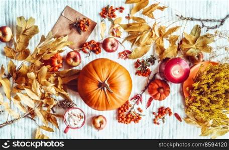 Autumn lifestyle with pumpkin,  envelope, yellow fall leaves, hot chocolate cup, candles and apples at white blanket backdrop. Seasonal flat lay background. Cozy time at home. Top view