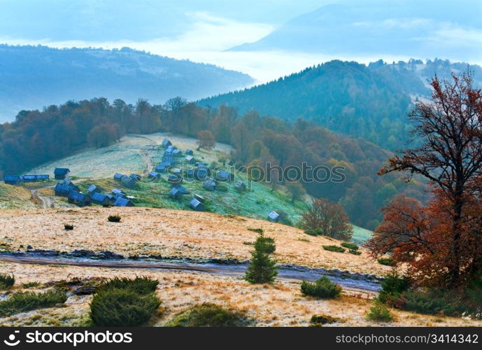 Autumn misty morning mountain hill with country road and cattle sheds (Carpathian Mt&rsquo;s, Ukraine).