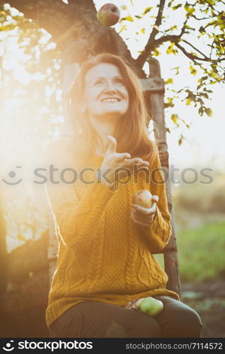 autumn mood - fun girl and apples in the garden at sunset