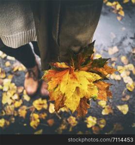 autumn mood - teen girl holding a red maple leaf in her hand