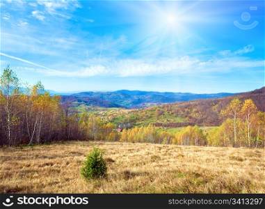 Autumn mountain country landscape with village ,birch trees and sunshine in sky (Carpathian, Ukraine).