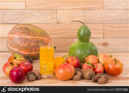 Autumn nature fruits concept. Fall fruits and orange juice, on a wooden table, studio picture