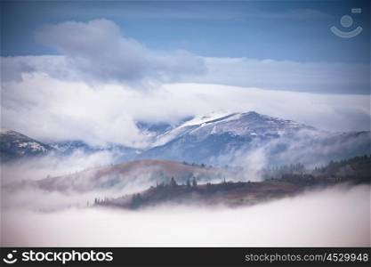 Autumn, November foggy and snowy morning in Carpathian mountain panorama.