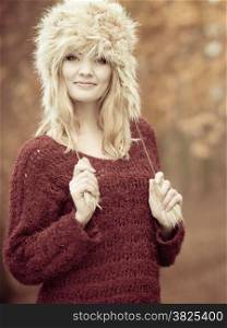 Autumn or winter fashion. Happy young woman wearing fashionable wintertime clothes fur cap outdoor portrait