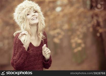 Autumn or winter fashion. Happy young woman wearing fashionable wintertime clothes fur cap outdoor portrait