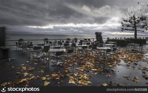 Autumn outdoor scenery with empty tables and wet chairs, on the terrace of a restaurant on the shore of Lake Constance, in Friedrichshafen, Germany.