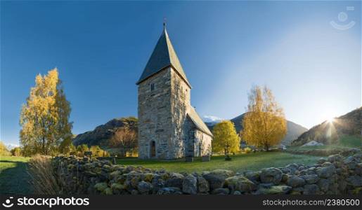Autumn panoramic landscape with a norwegian countryside church at sunset